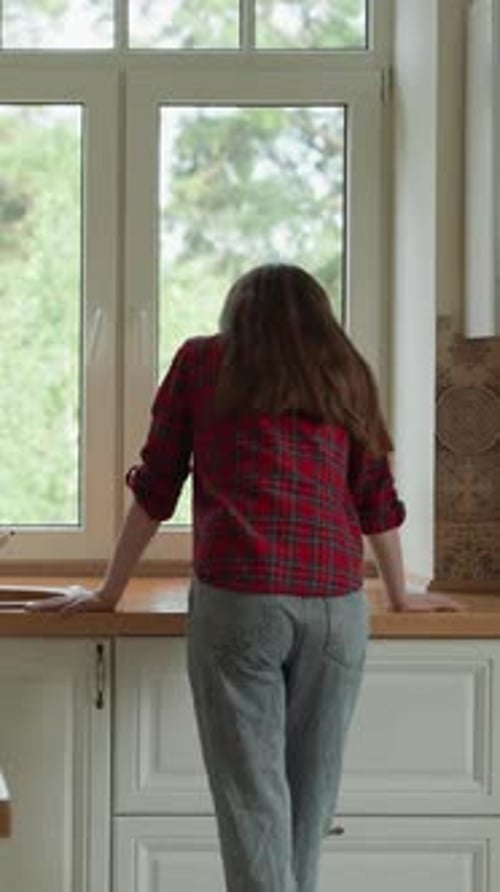 Woman Leaning on Kitchen Counter Looking out Window