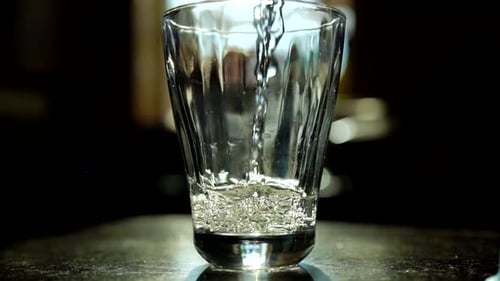 Pouring water into glass in slow motion