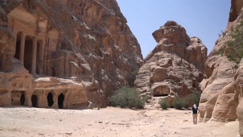 Little Petra, Jordan. Male Tourist Walking in Front of Ancient Temple Carved in Sandstone Cliff, Anc