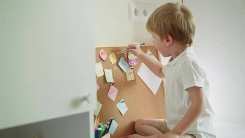 Blond Preschooler Draws with Ballpen on Piece of Paper