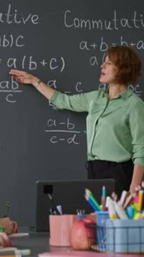 Teacher Explains Math to Students at Chalkboard