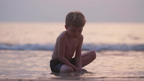 Child Playing in Sand at Ocean Beach Sunset