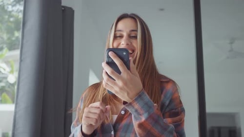 Excited Woman Looks at Phone With Cheering Gesture