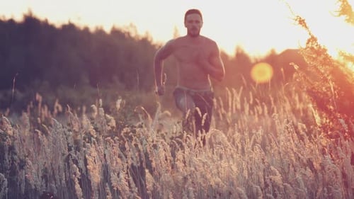 Shirtless Man Running Through Tall Grass at Sunset