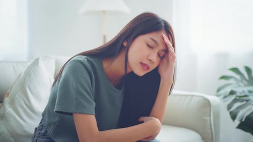 Sad tired young asian woman touching forehead having headache migraine or depression