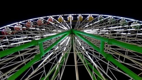 Brightly Lit Ferris Wheel Ride Spinning at Night at a Carnival Amusement Park Theme Park Fair Thrill