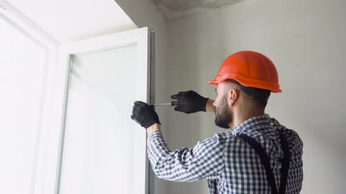 Worker Installs and Adjusts a New Plastic Window in House