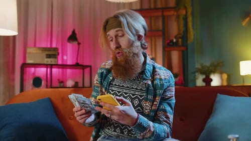 Blonde man with beard using phone and money