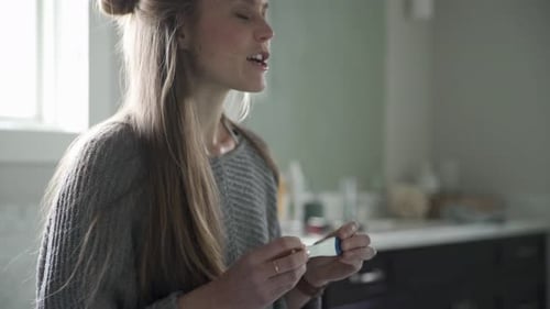 Woman Looks at Pregnancy Test in Bathroom