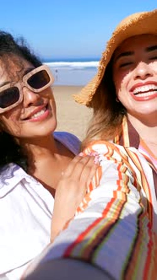 Two Cheerful Women Taking a Selfie Video at the Beach