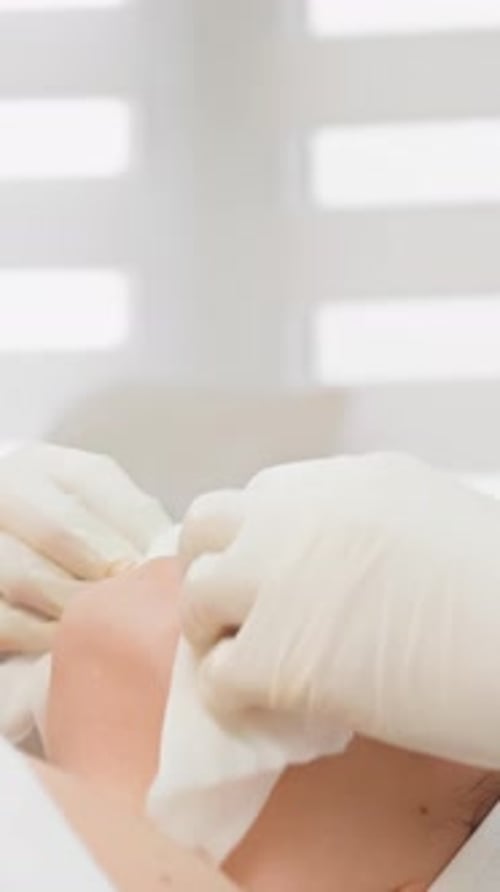 Woman receiving facial cleaning with cotton pad