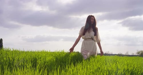 Woman Walking Through Lush Green Grassy Field