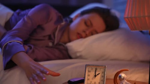 Woman Lying Awake at Midnight with Alarm Clock in Focus