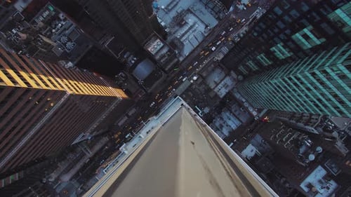 NYC: Midtown Manhattan skyscraper looking down over the edge, onto traffic below, with yellow taxi c