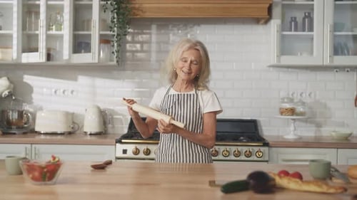 Carefree Old Woman Enjoying Music and Dancing Alone in Home Kitchen Portrait Charming Elderly Lady