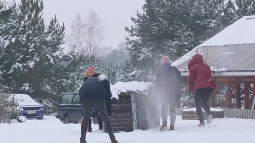 Group of friends playing and throwing snowballs at each other in a forest of Norway in slow motion.