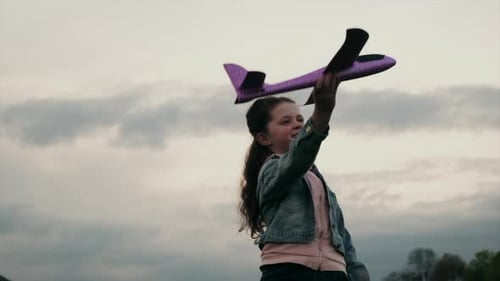 Girl Plays with Toy Plane in Open Field