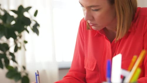 Woman Writing at Desk in Bright Home Office