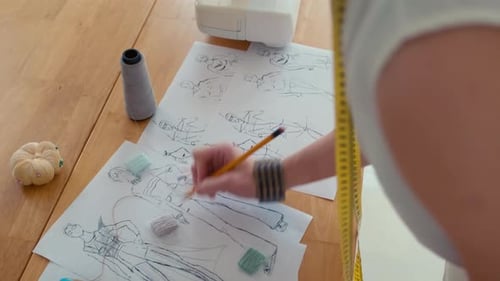 Fashion Designer Sketching Clothing Designs at Table