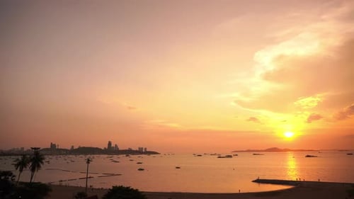 Gorgeous seascape with the sun setting to the right of a large city skyline.