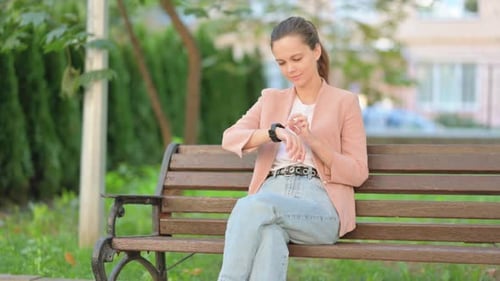 Woman Using Smart Watch on Park Bench