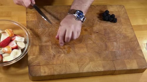 Cutting mandarin orange and blackberries for fruit smoothie.