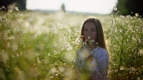Golden Hour Slow Motion Footage of Woman Smelling Flowers in Blossoming Meadow