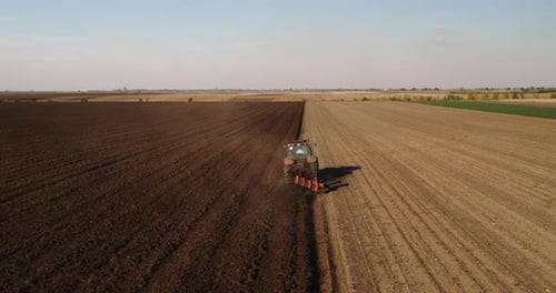 Tractor Tilling Vast Rural Field From Above