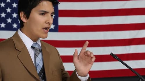 Young Adult Giving a Speech in Front of Flag