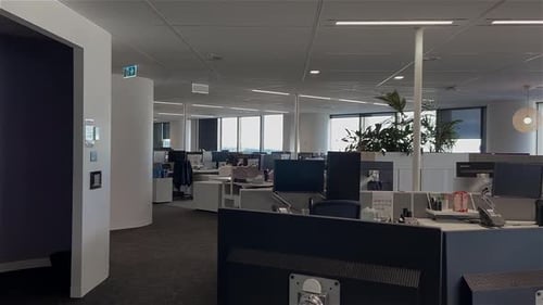 High quality dolly shot over empty desks in a large and deserted office building with unattended wor