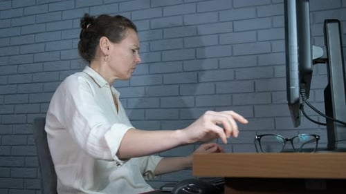 Woman Using Eye Drops at Her Desk