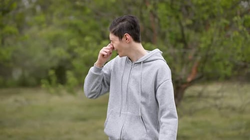 Un adolescent se couvre le nez avec les mains en grimaçant et en toussant à cause d'une odeur suffocante pour jeune homme
