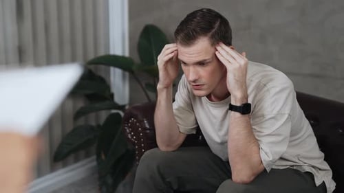 Worried Man Sitting on Couch Talking to Doctor
