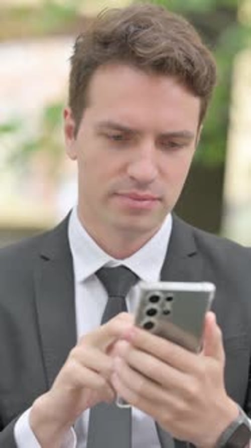 Young Man Using Cell Phone, Disappointed with Results