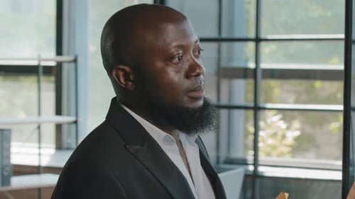 Selbstbewusster afrikanischer Marketingspezialist kommt zu transparentem Karton in modernem Büropapier