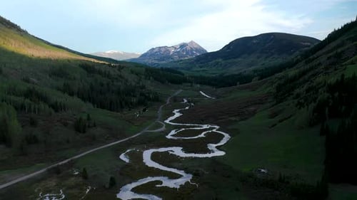 A meandering fresh-water river is seen from above in the mountain valleys on a beautiful summer day