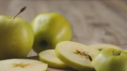 Green Apples and Slices with Knife on Wooden Surface