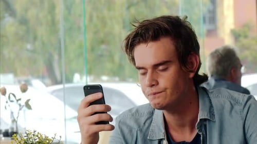 Casual Man Using Touch Screen Mobile Phone in Cafe