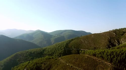 Dolly, muévete por encima de una montaña. Vista aérea desde arriba, vista desde arriba de la carretera a través de los árboles. 4k Portugal