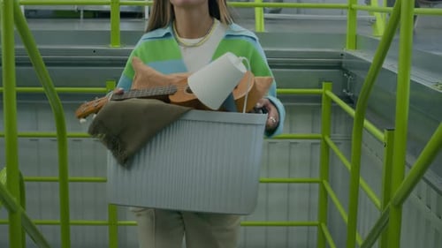 Femme avec boîte montant l'escalier de l'entrepôt