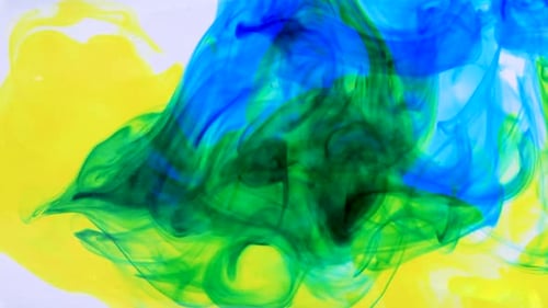 Yellow Blue Glitter Ink Spreading in Water Glass. Abstract Colorful Background with White Color