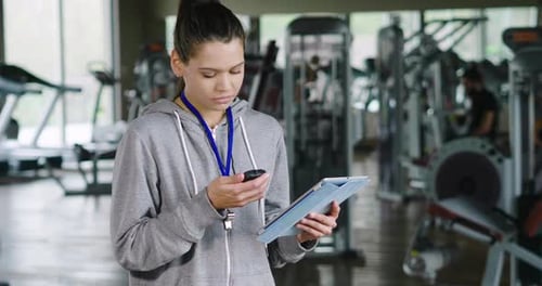 Smiling Woman Using Tablet in Modern Gym