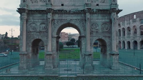 Aerial drone view through the Arco di Costantino arch in front of the Colosseum, in Rome, Italy