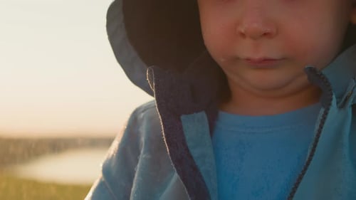 Sad Child in Raincoat on Rainy Day