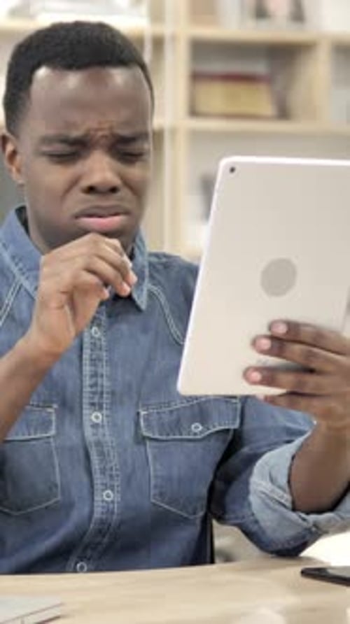 Young Man Using a Tablet Indoors at a Table