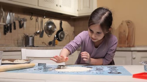 Little Girl Making Cookies Using Cookie Cutters in Kitchen