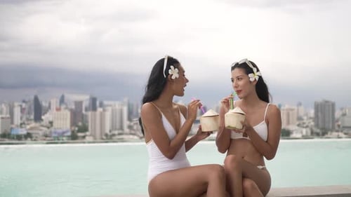 Female friends spend leisure activity at rooftop swimming pool.