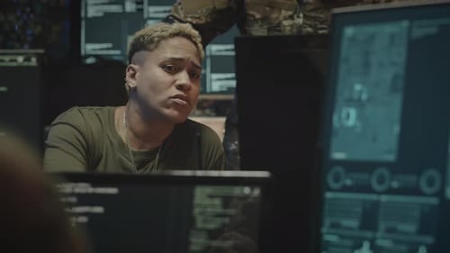 Person in Dark Room Looking at Computer Monitors