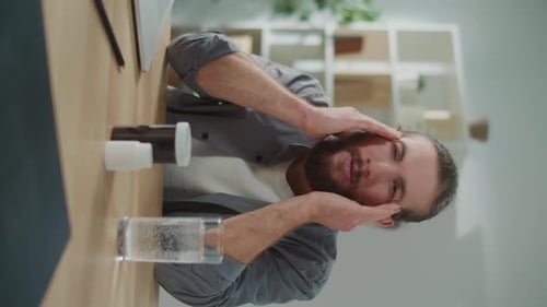 Man With Headache Rubbing Temples Near Pills