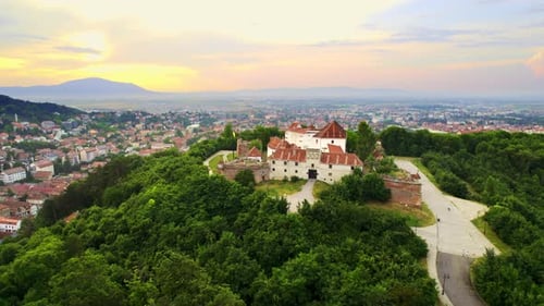 Aerial drone view of The Citadel in Brasov at sunset, Romania. Medieval fortress on the top of a hil